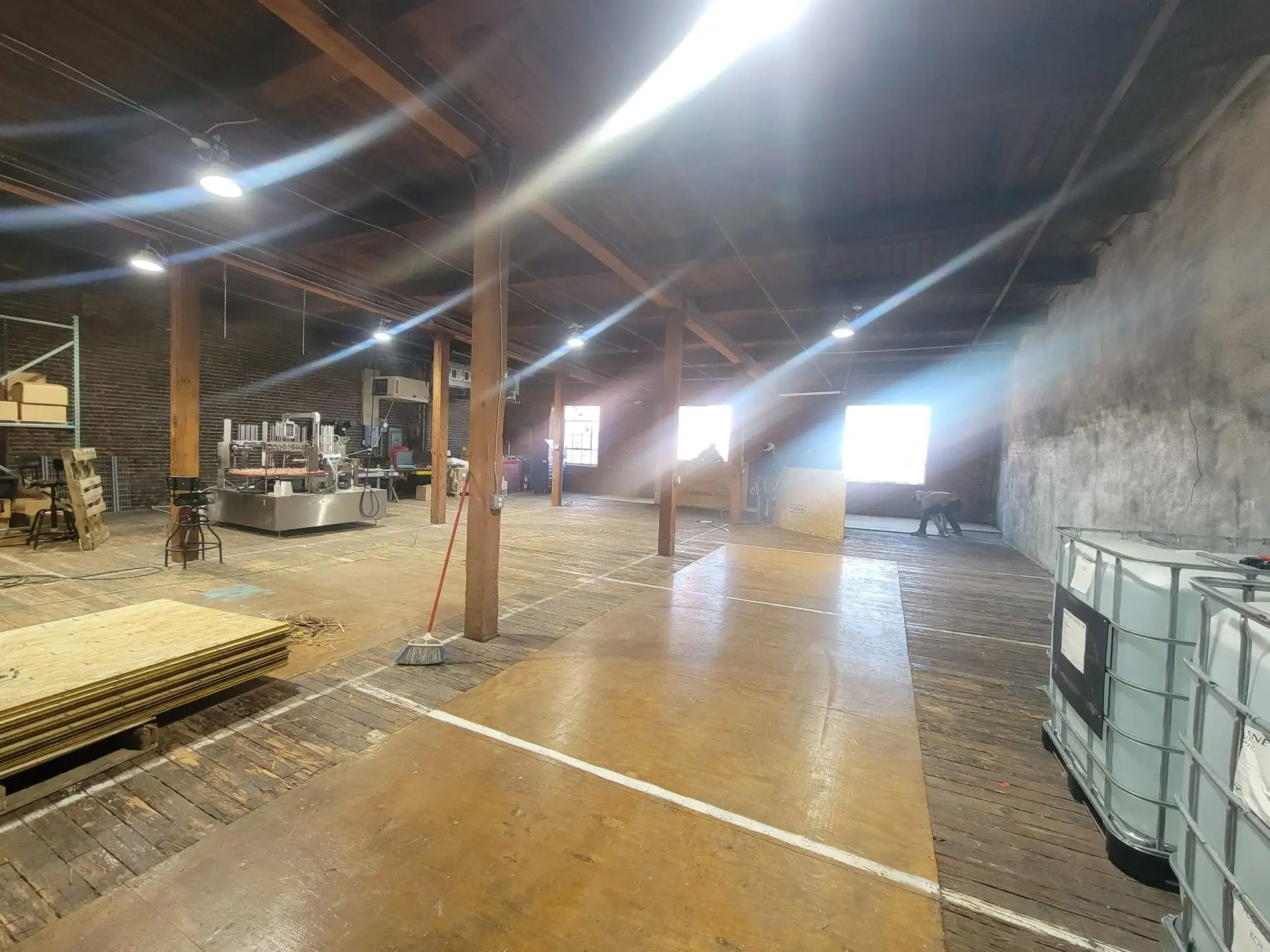 Open commercial floor cleared back to timber posts and brick, materials stacked ready