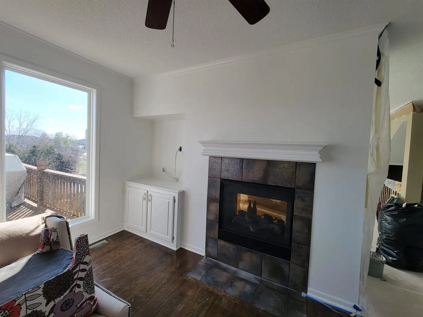 Finished living room with a tiled fireplace surround and refinished wood floor