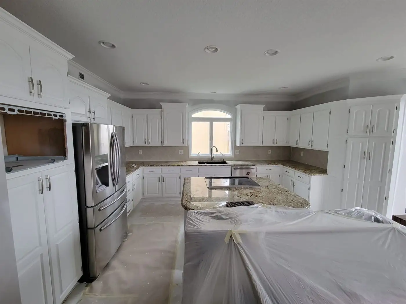 Kitchen with white cabinets and stainless appliances after refinishing