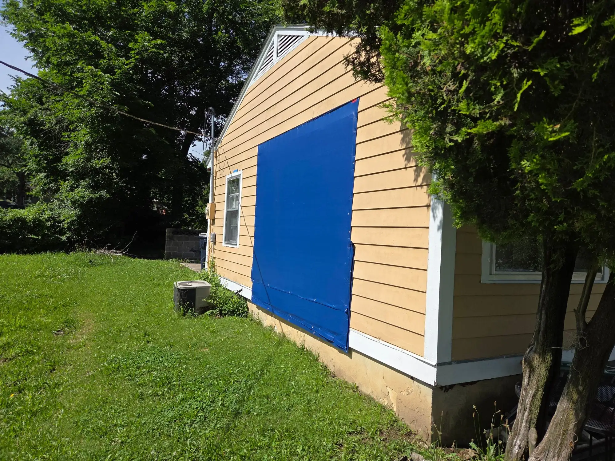 House gable with a section of siding stripped back and boarded over during the repair